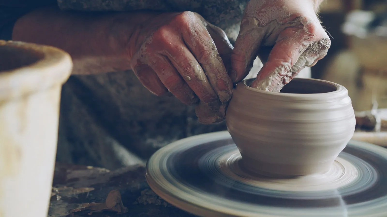Artisan skillfully shapes clay on a spinning wheel, showcasing traditional pottery techniques.